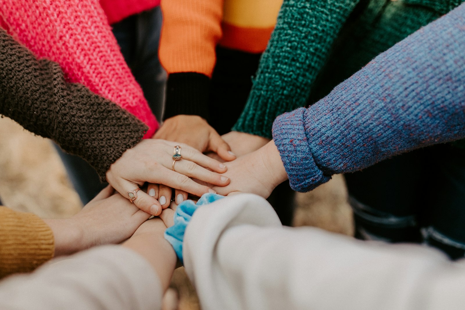 A circle of hands from a diverse group of people joined together in support