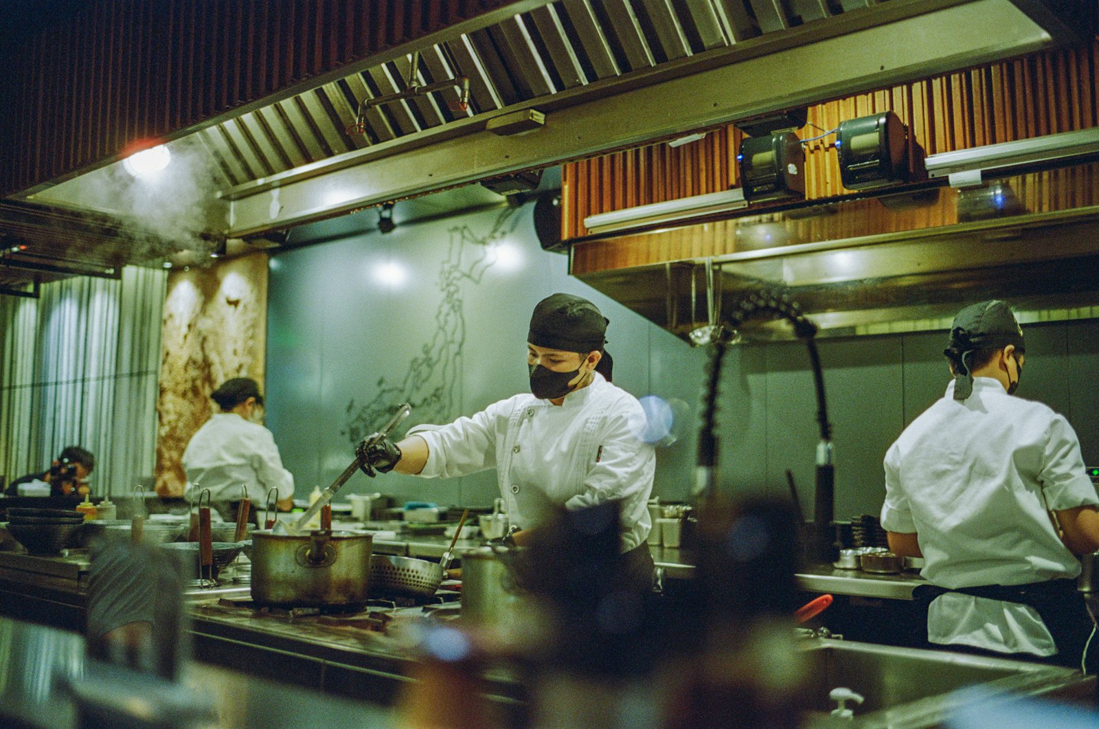 Restaurant kitchen staff in uniform working together preparing food